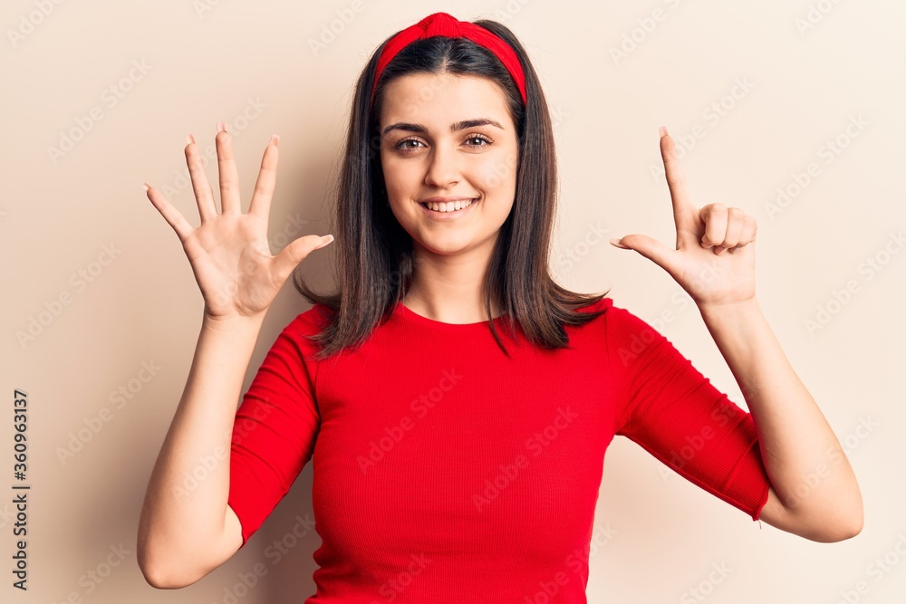 Young beautiful girl wearing casual t shirt and diadem showing and pointing up with fingers number seven while smiling confident and happy. Young beautiful girl wearing casual t shirt and diadem showing and pointing up with fingers number seven while smiling confident and happy.