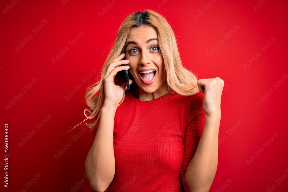 Beautiful blonde woman having conversation talking on the smartphone over red background screaming proud and celebrating victory and success very excited, cheering emotion Beautiful blonde woman having conversation talking on the smartphone over red background screaming proud and celebrating victory and success very excited, cheering emotion