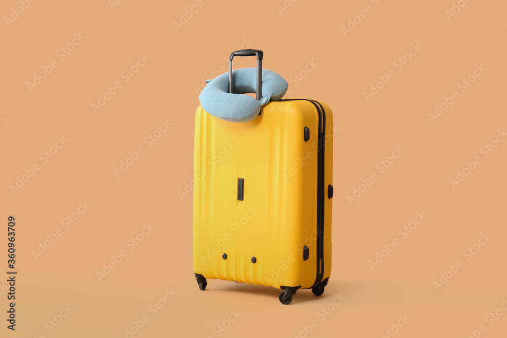 Packed suitcase and travel pillow on color background Packed suitcase and travel pillow on color background