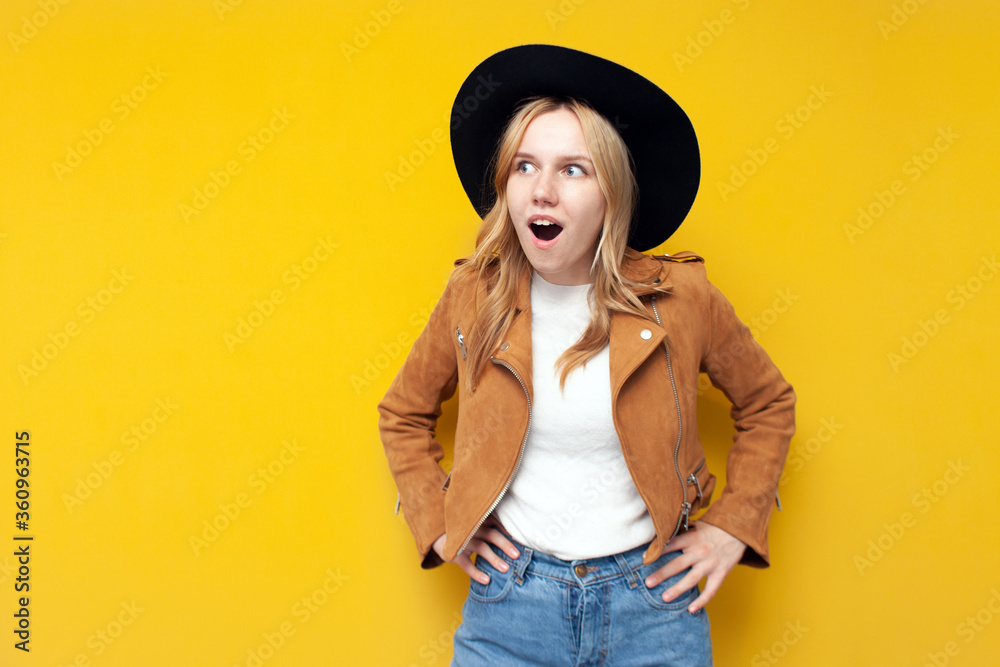 shocked girl in autumn fashionable clothes is surprised on a yellow isolated background, a woman in a jacket and hat says wow, copy space shocked girl in autumn fashionable clothes is surprised on a yellow isolated background, a woman in a jacket and hat says wow, copy space