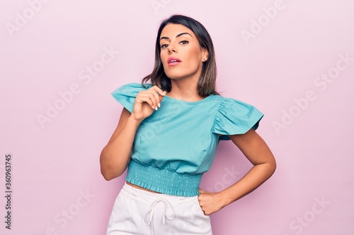 Young beautiful brunette woman standing over isolated pink background