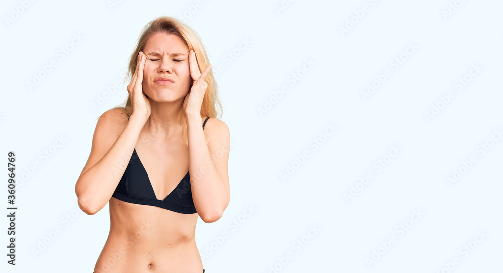 Fototapeta premium Young beautiful blonde woman wearing bikini with hand on head, headache because stress. suffering migraine.