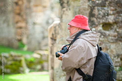 An elderly man with a camera in ancient ruins