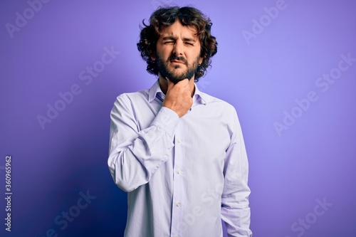 Fototapeta Naklejka Na Ścianę i Meble -  Young handsome business man with beard wearing shirt standing over purple background Touching painful neck, sore throat for flu, clod and infection