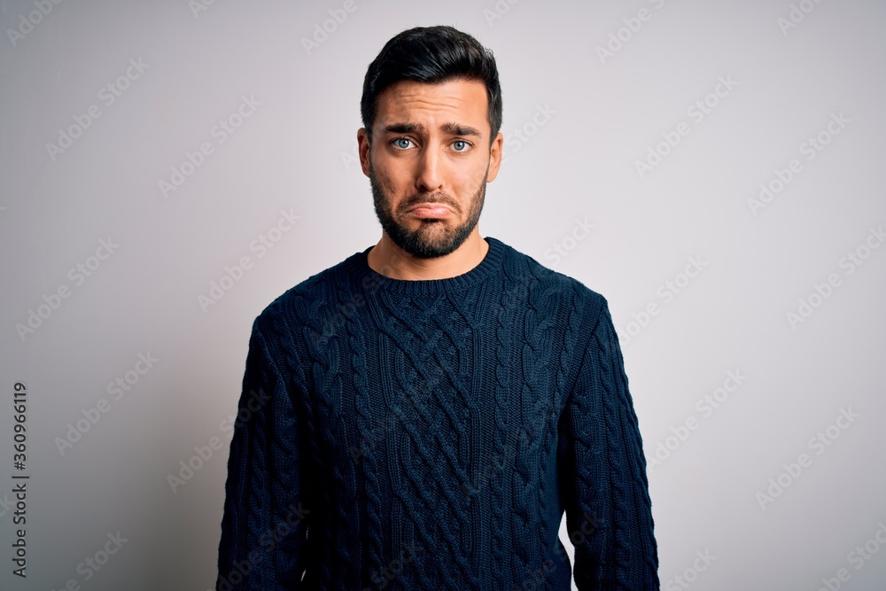 Young handsome man with beard wearing casual sweater standing over white background depressed and worry for distress, crying angry and afraid. Sad expression. Young handsome man with beard wearing casual sweater standing over white background depressed and worry for distress, crying angry and afraid. Sad expression.