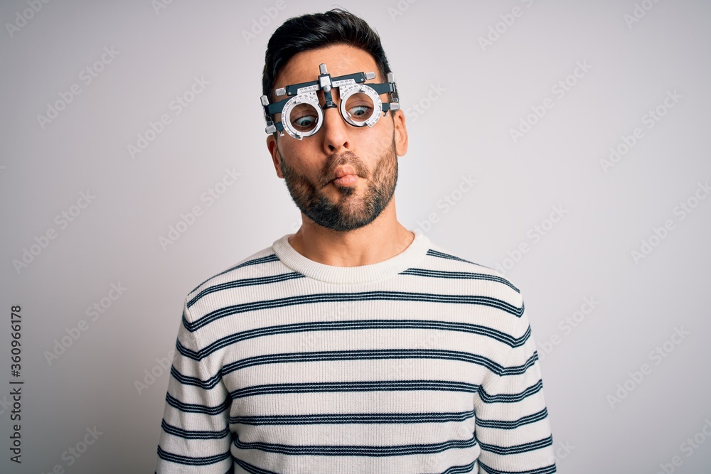 Young handsome man with beard wearing optometry glasses over isolated white background making fish face with lips, crazy and comical gesture. Funny expression. Young handsome man with beard wearing optometry glasses over isolated white background making fish face with lips, crazy and comical gesture. Funny expression.