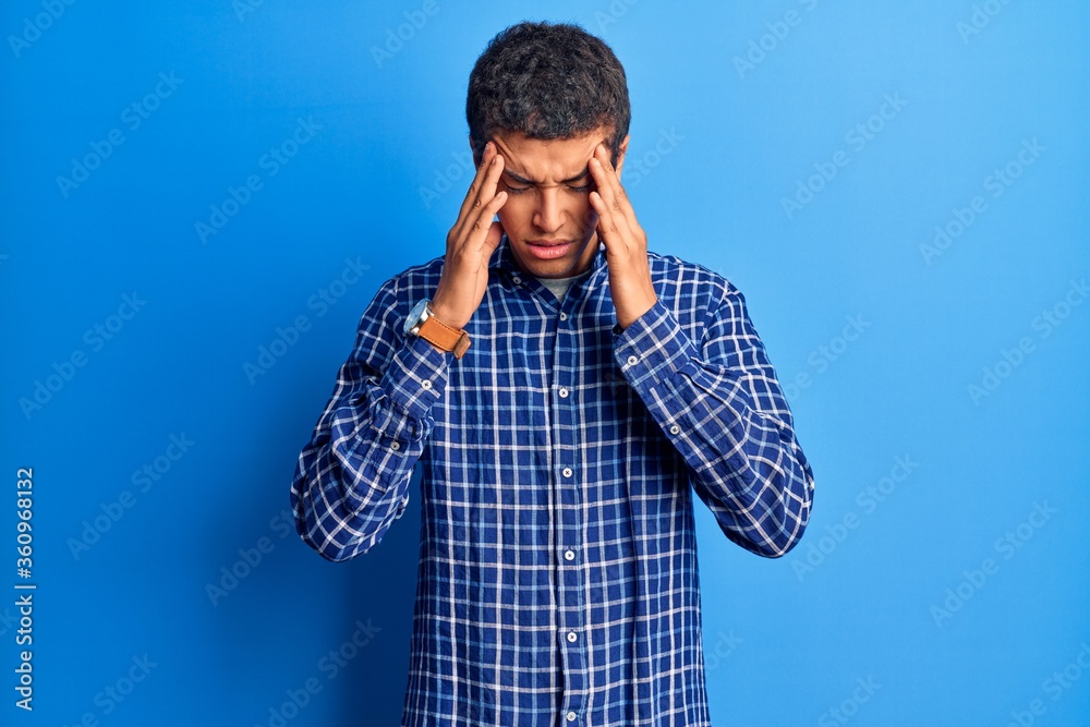 Young african amercian man wearing casual clothes with hand on head for pain in head because stress. suffering migraine. Young african amercian man wearing casual clothes with hand on head for pain in head because stress. suffering migraine.