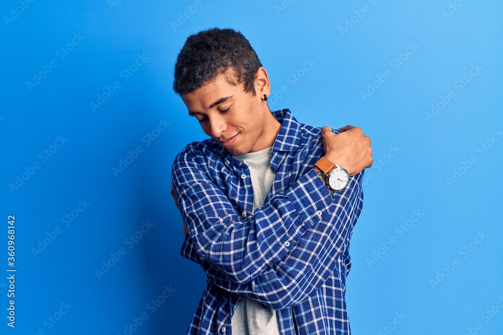 Young african amercian man wearing casual clothes hugging oneself happy and positive, smiling confident. self love and self care Young african amercian man wearing casual clothes hugging oneself happy and positive, smiling confident. self love and self care