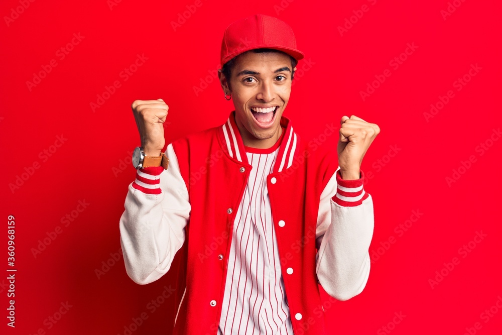 Young african amercian man wearing baseball uniform screaming proud, celebrating victory and success very excited with raised arms Young african amercian man wearing baseball uniform screaming proud, celebrating victory and success very excited with raised arms
