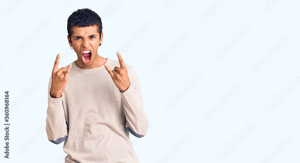 Young african amercian man wearing casual clothes shouting with crazy expression doing rock symbol with hands up. music star. heavy concept.