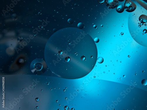 Closeup bubbles oil in water with blue light blurred abstract background, macro image ,droplets for card design 