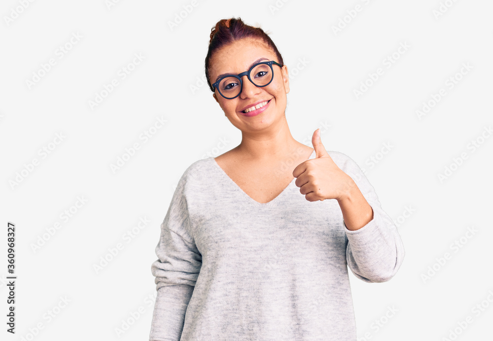 Young latin woman wearing casual clothes doing happy thumbs up gesture with hand. approving expression looking at the camera showing success. Young latin woman wearing casual clothes doing happy thumbs up gesture with hand. approving expression looking at the camera showing success.