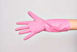 Hand of caucasian young woman wearing pink cleaning glove. Showing fingers doing number five over isolated white background