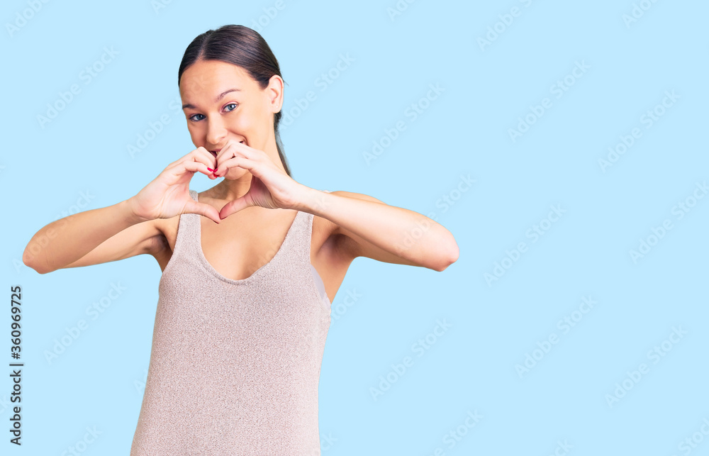 Beautiful brunette young woman wearing casual dress smiling in love showing heart symbol and shape with hands. romantic concept. Beautiful brunette young woman wearing casual dress smiling in love showing heart symbol and shape with hands. romantic concept.