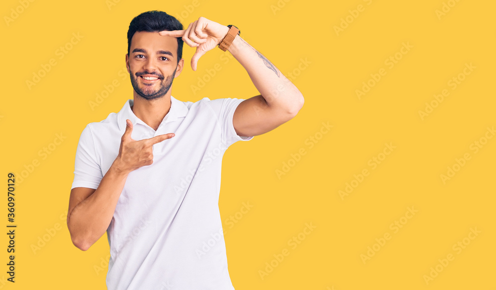 Young handsome hispanic man wearing casual clothes smiling making frame with hands and fingers with happy face. creativity and photography concept. Young handsome hispanic man wearing casual clothes smiling making frame with hands and fingers with happy face. creativity and photography concept.