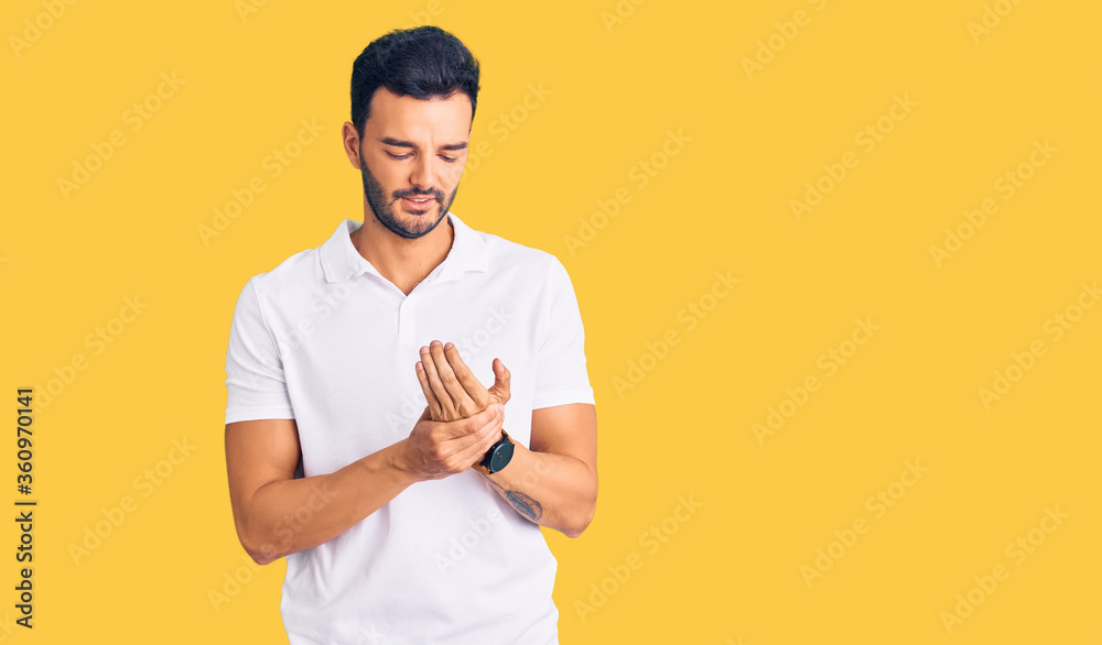 Young handsome hispanic man wearing casual clothes suffering pain on hands and fingers, arthritis inflammation Young handsome hispanic man wearing casual clothes suffering pain on hands and fingers, arthritis inflammation