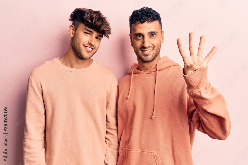 Young gay couple wearing casual clothes showing and pointing up with fingers number four while smiling confident and happy. Young gay couple wearing casual clothes showing and pointing up with fingers number four while smiling confident and happy.