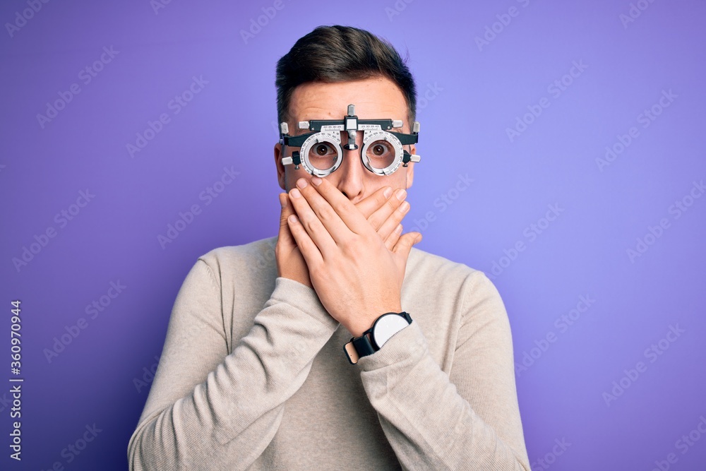 Young handsome caucasian man wearing optometrical glasses over purple background shocked covering mouth with hands for mistake. Secret concept.