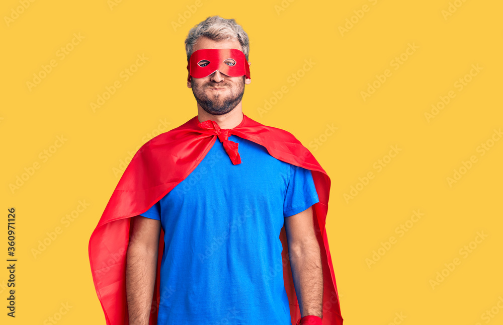 Young blond man wearing super hero custome puffing cheeks with funny face. mouth inflated with air, crazy expression. Young blond man wearing super hero custome puffing cheeks with funny face. mouth inflated with air, crazy expression.