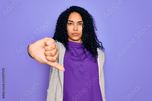 Young african american sporty woman wearing casual sweatshirt over purple background looking unhappy and angry showing rejection and negative with thumbs down gesture. Bad expression. © Krakenimages.com