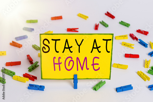 Writing note showing Stay At Home. Business concept for movement control restricting individuals from getting exposed publicly Colored clothespin papers empty reminder white floor background office