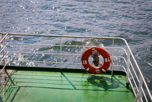 Buoy or lifebuoy ring on shipboard in evening sea. Flotation device on ship side on seascape. Safety, rescue, life preserver. Water travel, voyage, journey. Wanderlust, vacation, trip