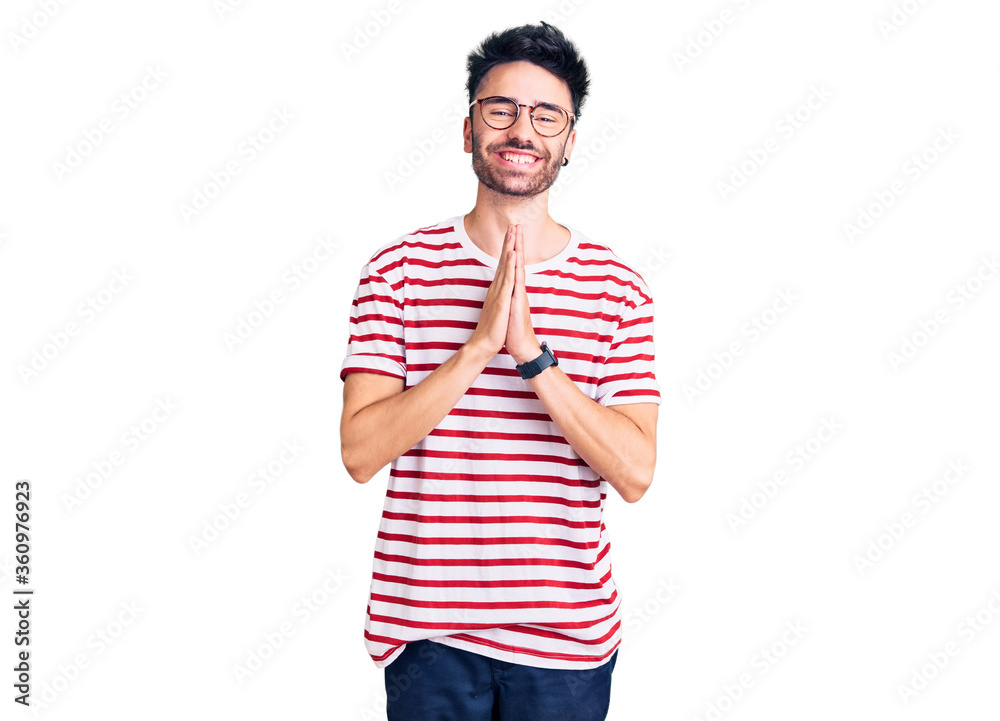 Young hispanic man wearing casual clothes praying with hands together asking for forgiveness smiling confident. Young hispanic man wearing casual clothes praying with hands together asking for forgiveness smiling confident.