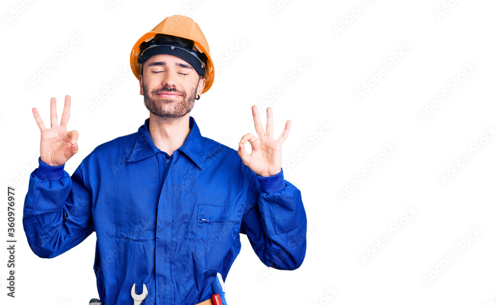 Young hispanic man wearing worker uniform relaxed and smiling with eyes closed doing meditation gesture with fingers. yoga concept.