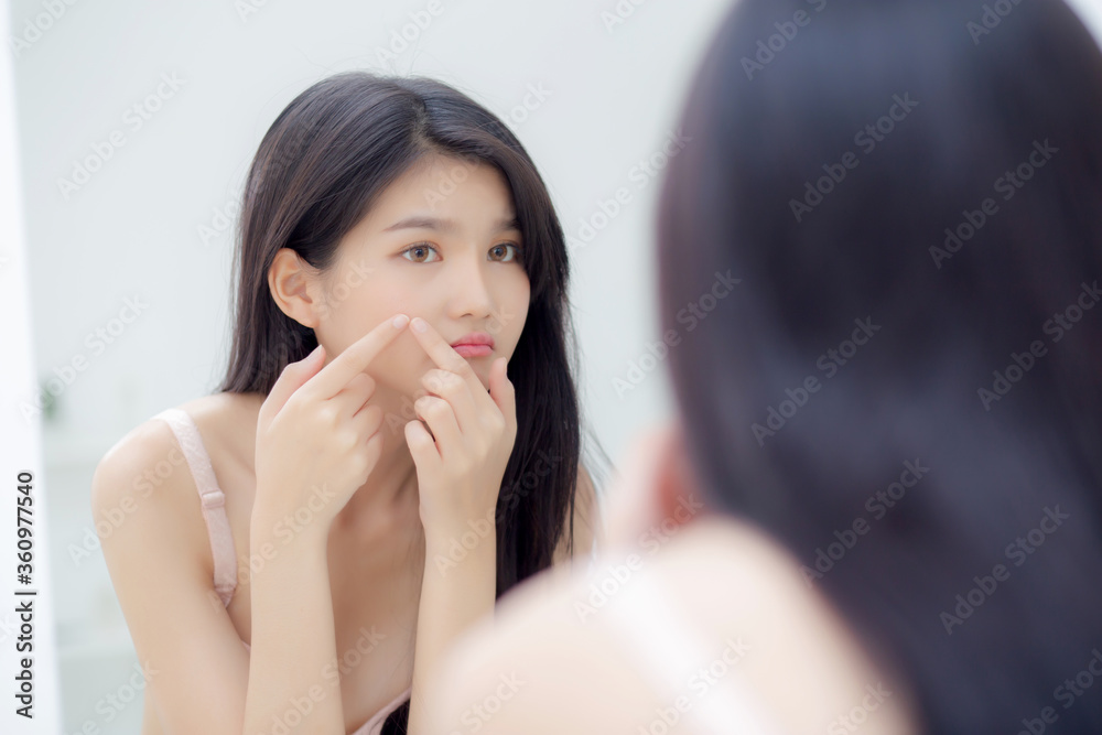 Beautiful young asian woman looking the mirror and touch face is a acne, zit treatment, beauty girl problem beauty and skin with wrinkled on facial in the room at home, makeup and cosmetic concept. Beautiful young asian woman looking the mirror and touch face is a acne, zit treatment, beauty girl problem beauty and skin with wrinkled on facial in the room at home, makeup and cosmetic concept.