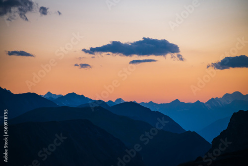 Foto Colorful dawn landscape with beautiful mountains silhouettes and golden gradient sky with blue clouds