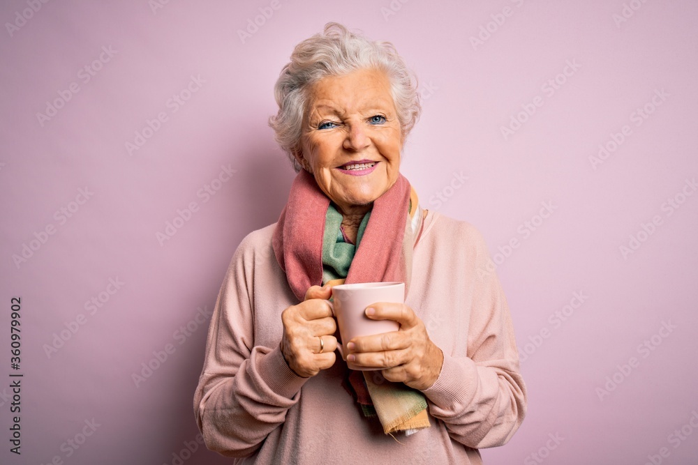 Senior beautiful grey-haired woman drinking mug of coffee over isolated pink background with a happy face standing and smiling with a confident smile showing teeth Senior beautiful grey-haired woman drinking mug of coffee over isolated pink background with a happy face standing and smiling with a confident smile showing teeth