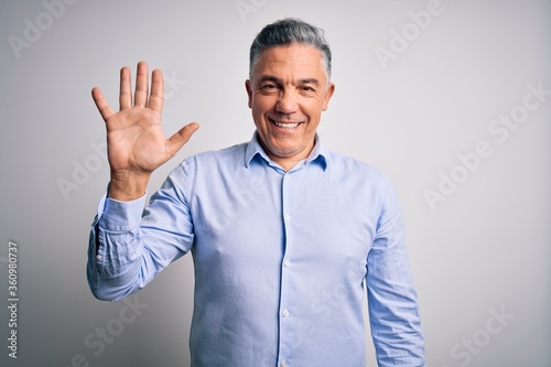 Middle age handsome grey-haired business man wearing elegant shirt over white background showing and pointing up with fingers number five while smiling confident and happy. © Krakenimages.com