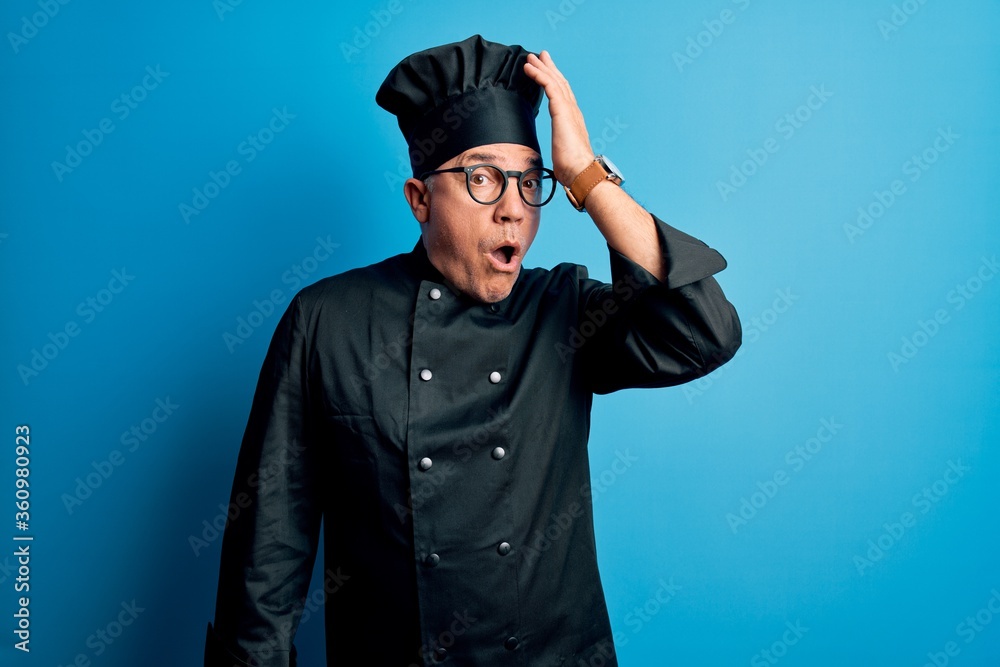 Middle age handsome grey-haired chef man wearing cooker uniform and hat surprised with hand on head for mistake, remember error. Forgot, bad memory concept. Middle age handsome grey-haired chef man wearing cooker uniform and hat surprised with hand on head for mistake, remember error. Forgot, bad memory concept.