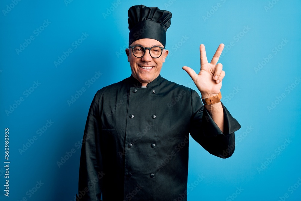 Middle age handsome grey-haired chef man wearing cooker uniform and hat showing and pointing up with fingers number three while smiling confident and happy. Middle age handsome grey-haired chef man wearing cooker uniform and hat showing and pointing up with fingers number three while smiling confident and happy.