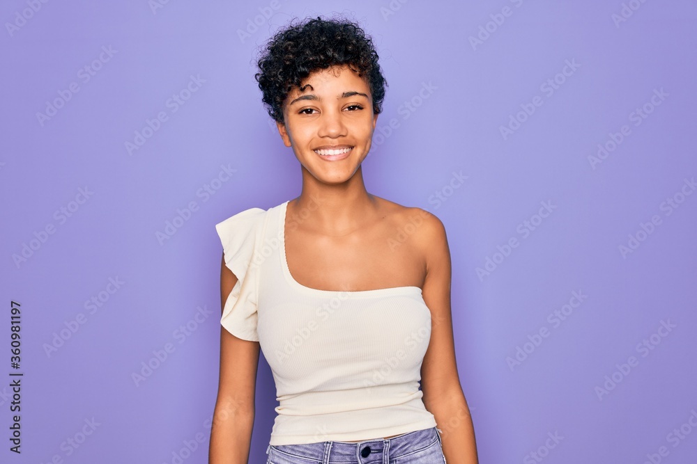Young beautiful african american afro woman wearing casual t-shirt over purple background with a happy and cool smile on face. Lucky person. Young beautiful african american afro woman wearing casual t-shirt over purple background with a happy and cool smile on face. Lucky person.