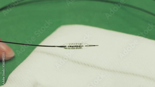 Finger pointing at stent, small metal object, taking off metal framework, percutaneous coronary intervention, close up photo