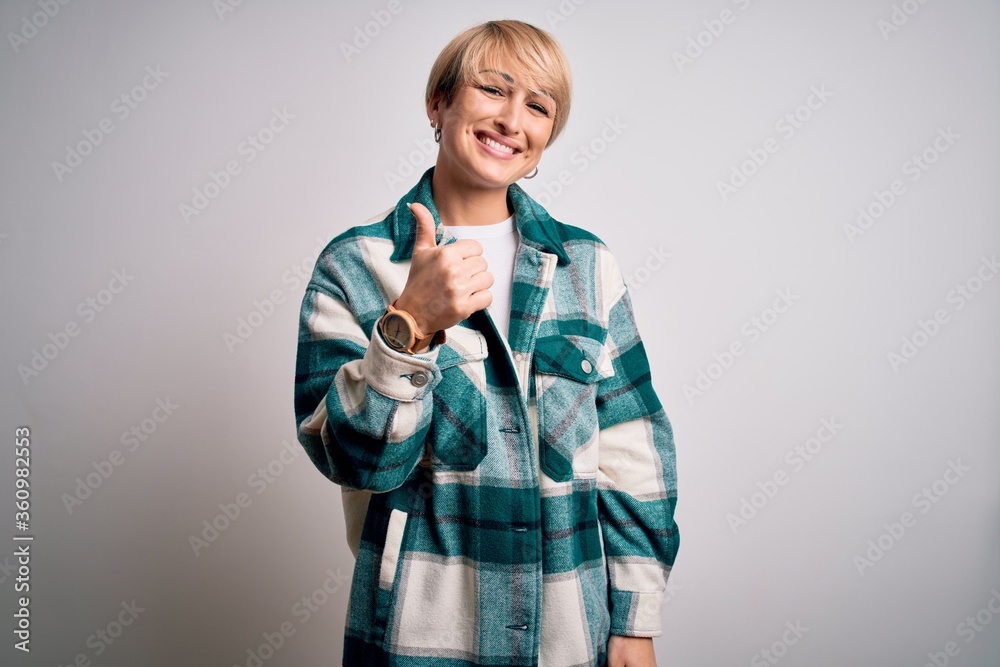 Young blonde woman with short hair wearing casual retro green shirt over isolated background doing happy thumbs up gesture with hand. Approving expression looking at the camera showing success. Young blonde woman with short hair wearing casual retro green shirt over isolated background doing happy thumbs up gesture with hand. Approving expression looking at the camera showing success.