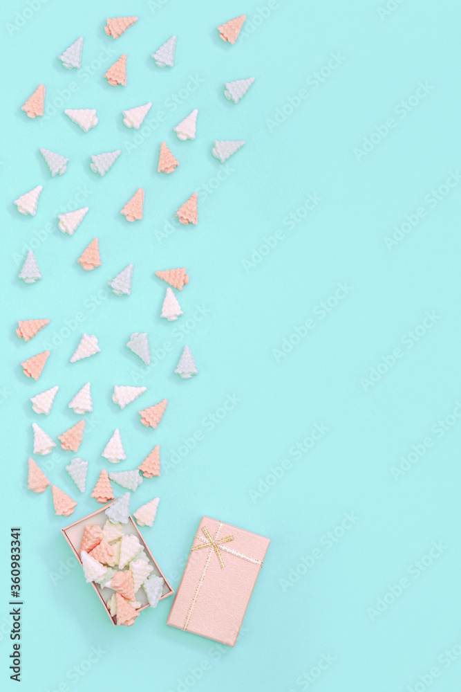 Small sweet chocolate candies in shape of Christmas trees is scattered from pink gift box. Candy creative for New Year and greeting card. Pastel colors - mint and pink. Small sweet chocolate candies in shape of Christmas trees is scattered from pink gift box. Candy creative for New Year and greeting card. Pastel colors - mint and pink.