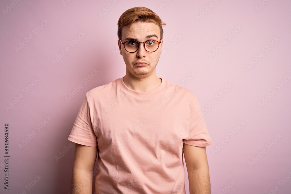 Young handsome redhead man wearing casual t-shirt standing over isolated pink background skeptic and nervous, frowning upset because of problem. Negative person. Young handsome redhead man wearing casual t-shirt standing over isolated pink background skeptic and nervous, frowning upset because of problem. Negative person.
