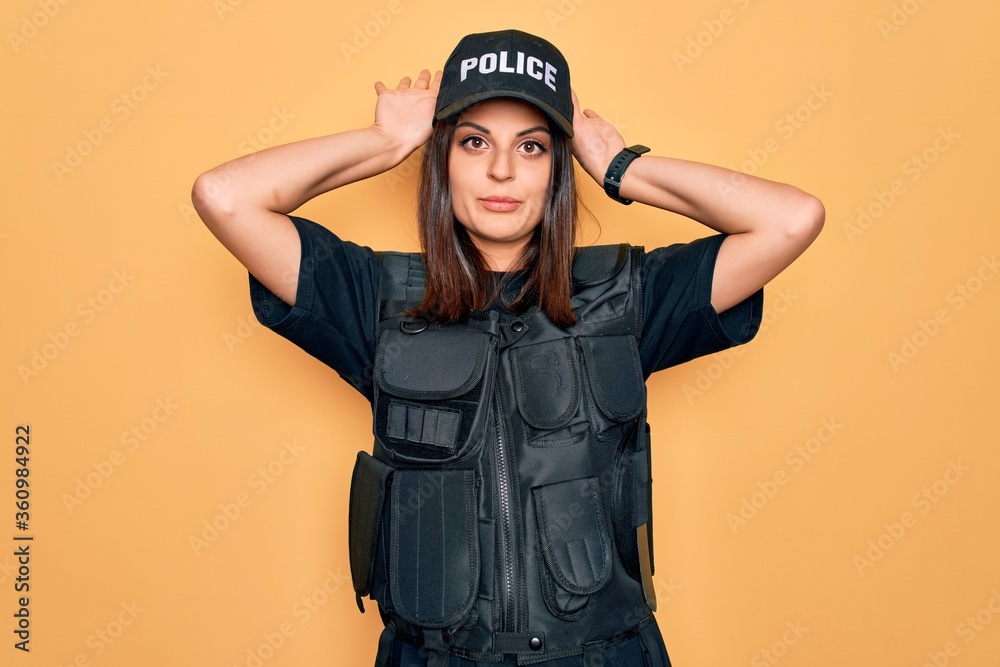 Young beautiful brunette policewoman wearing police uniform bulletproof and cap Doing bunny ears gesture with hands palms looking cynical and skeptical. Easter rabbit concept. Young beautiful brunette policewoman wearing police uniform bulletproof and cap Doing bunny ears gesture with hands palms looking cynical and skeptical. Easter rabbit concept.