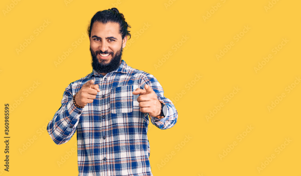 Young arab man wearing casual clothes pointing fingers to camera with happy and funny face. good energy and vibes. Young arab man wearing casual clothes pointing fingers to camera with happy and funny face. good energy and vibes.