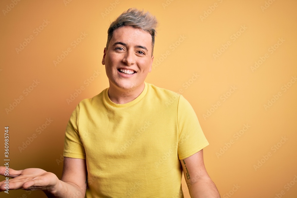 Young handsome modern man wearing yellow shirt over yellow isolated background smiling cheerful with open arms as friendly welcome, positive and confident greetings Young handsome modern man wearing yellow shirt over yellow isolated background smiling cheerful with open arms as friendly welcome, positive and confident greetings