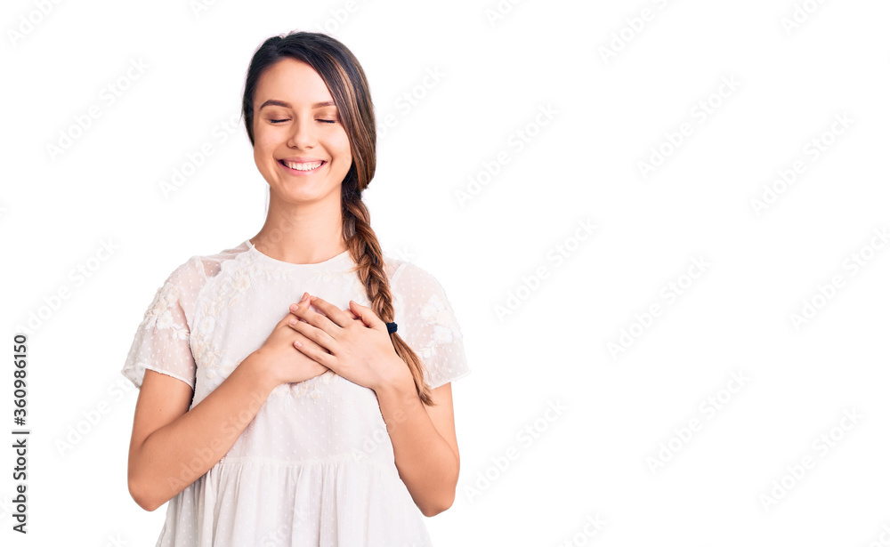Young beautiful girl wearing casual t shirt smiling with hands on chest with closed eyes and grateful gesture on face. health concept. Young beautiful girl wearing casual t shirt smiling with hands on chest with closed eyes and grateful gesture on face. health concept.
