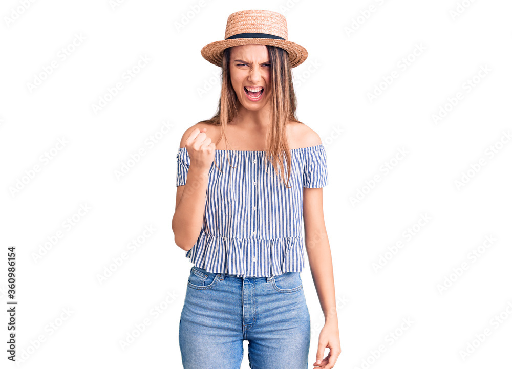 Young beautiful girl wearing hat and t shirt angry and mad raising fist frustrated and furious while shouting with anger. rage and aggressive concept. Young beautiful girl wearing hat and t shirt angry and mad raising fist frustrated and furious while shouting with anger. rage and aggressive concept.