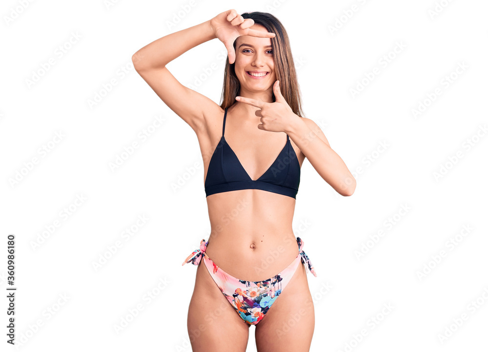 Young beautiful girl wearing bikini smiling making frame with hands and fingers with happy face. creativity and photography concept.