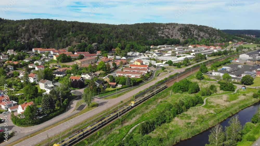 Train passing alongside small hillside town, establishing