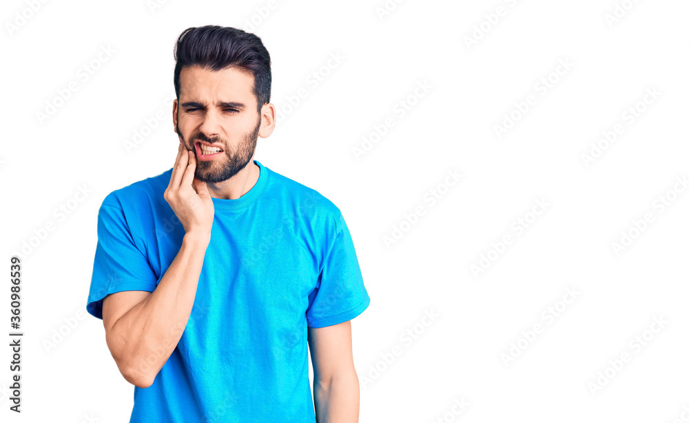 Young handsome man with beard wearing casual t-shirt touching mouth with hand with painful expression because of toothache or dental illness on teeth. dentist Young handsome man with beard wearing casual t-shirt touching mouth with hand with painful expression because of toothache or dental illness on teeth. dentist