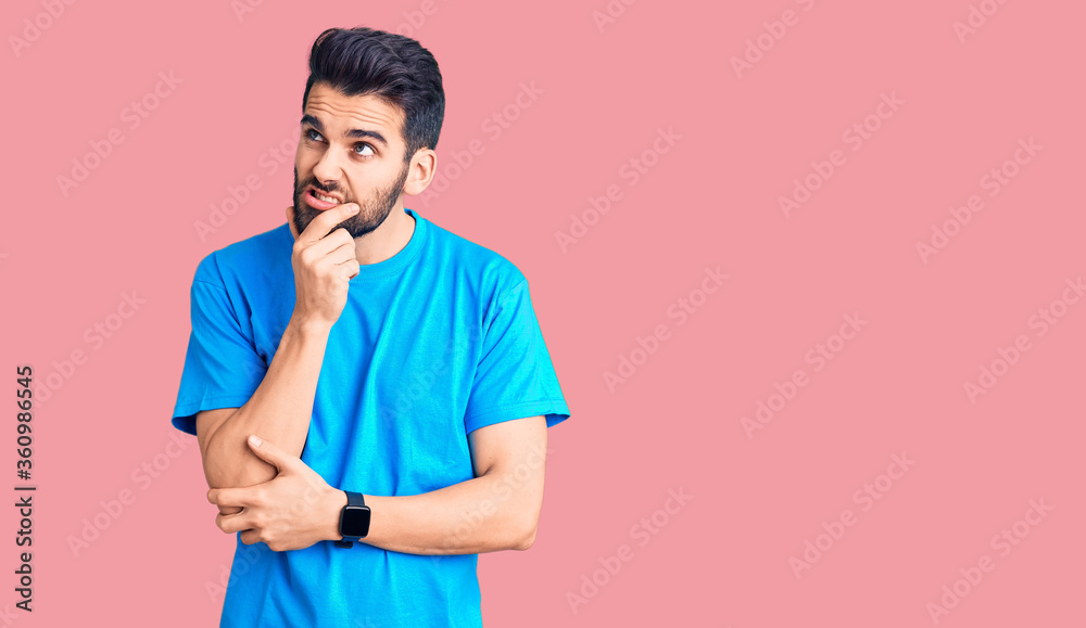 Young handsome man with beard wearing casual t-shirt thinking worried about a question, concerned and nervous with hand on chin Young handsome man with beard wearing casual t-shirt thinking worried about a question, concerned and nervous with hand on chin