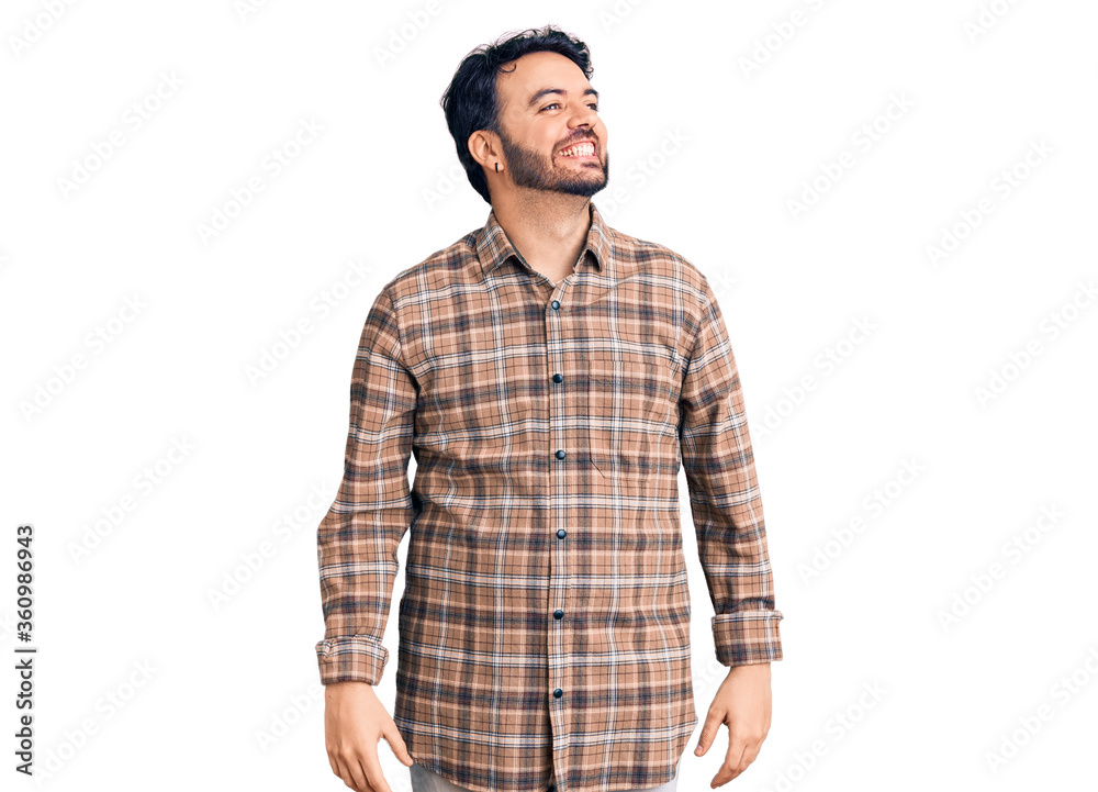 Young hispanic man wearing casual clothes looking away to side with smile on face, natural expression. laughing confident. Young hispanic man wearing casual clothes looking away to side with smile on face, natural expression. laughing confident.