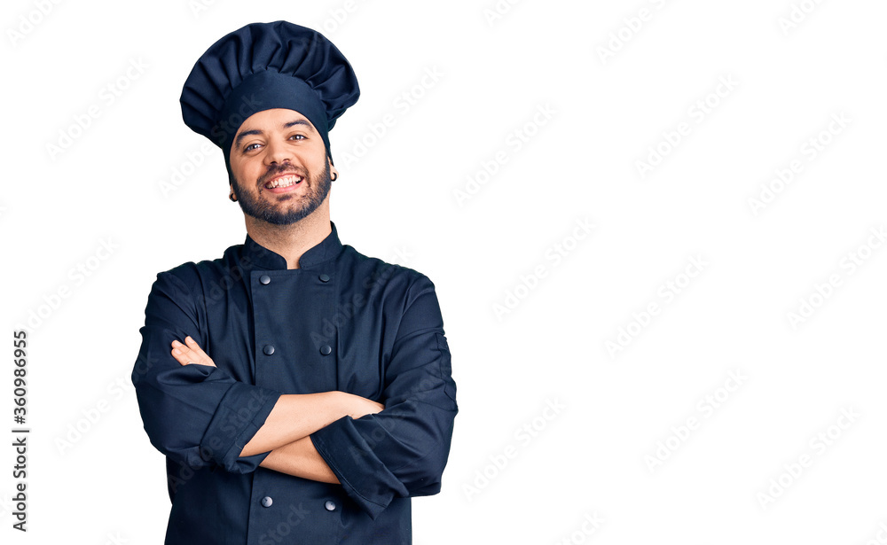 Young hispanic man wearing cooker uniform happy face smiling with crossed arms looking at the camera. positive person. Young hispanic man wearing cooker uniform happy face smiling with crossed arms looking at the camera. positive person.